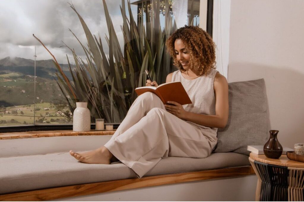 woman writing in journal focused at clean wooden desk in morning