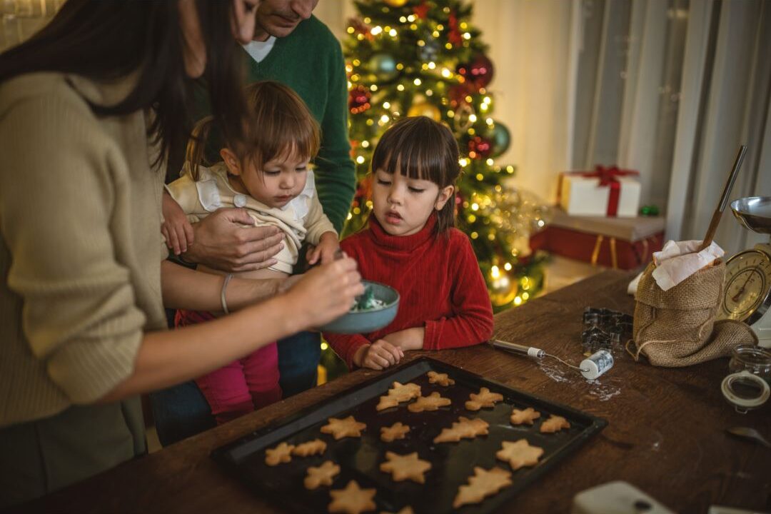 family baking cookies together and placing them into decorated gift boxes