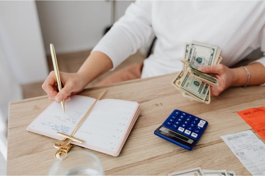 hand writing monthly budget in paper planner illustrating proactive financial systems