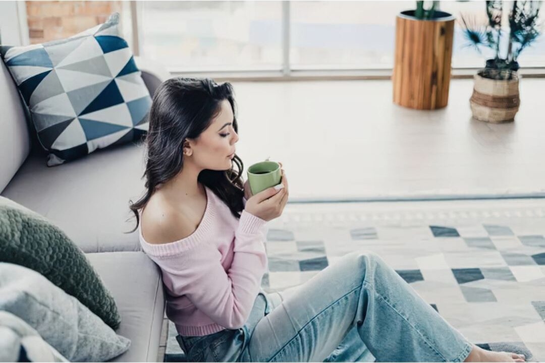 relaxed woman drinking tea in sparkling clean living room