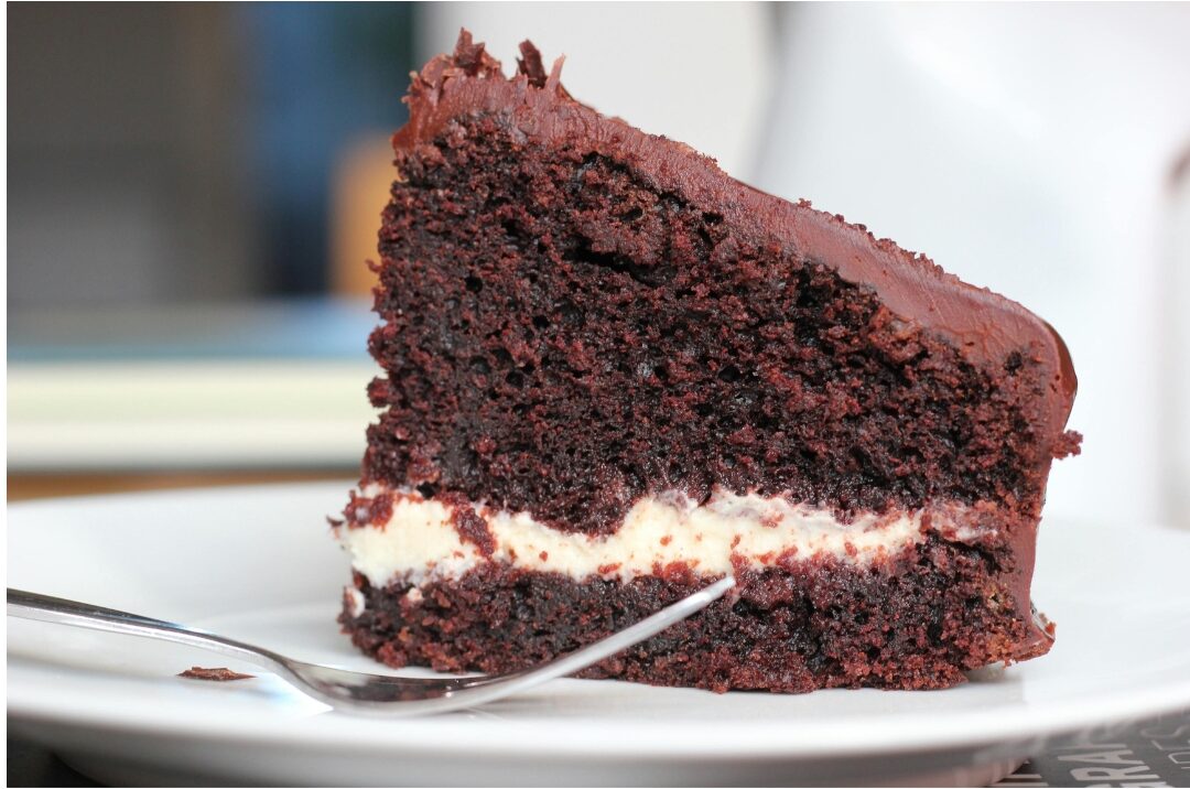 slice of rich dark chocolate resting on small ceramic plate"