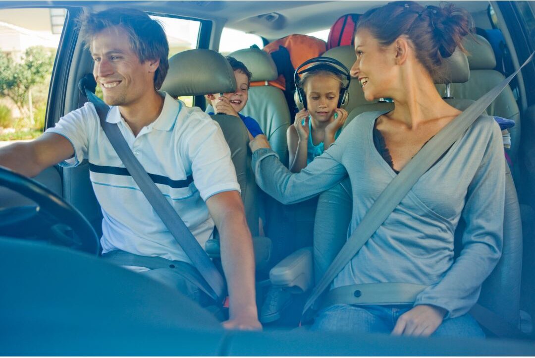 family riding in car laughing while parent drives along scenic country road