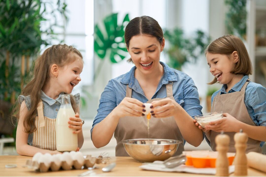 children helping parent make pancakes on wooden kitchen counter