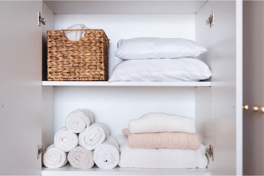 organized laundry room with folded white towels on wooden shelf