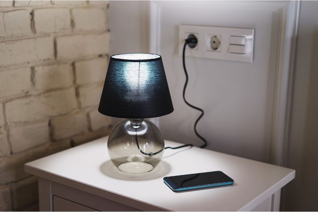 face down smartphone next to glowing ceramic table lamp