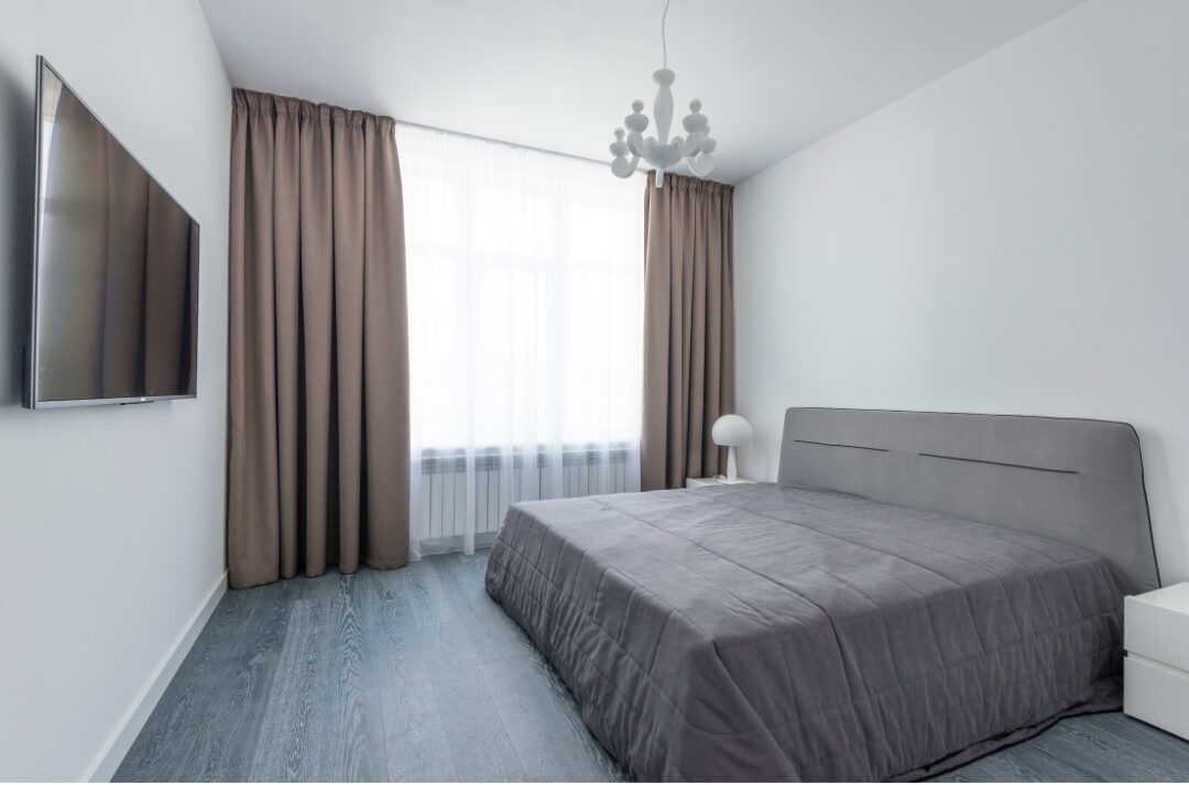 serene bedroom with dark blackout drapes framed against sunny window