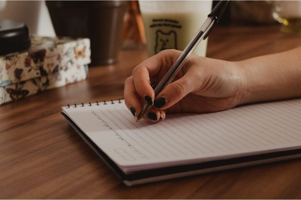 hand holding pen over notebook representing seventy two hour purchase pause