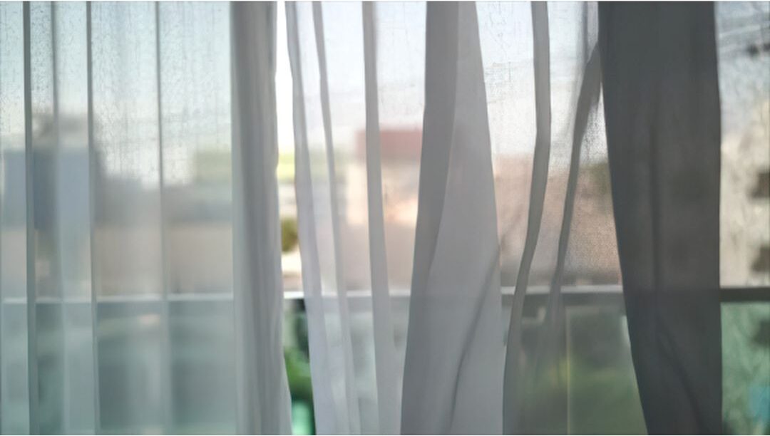 sheer white curtains blowing gently in open window breeze