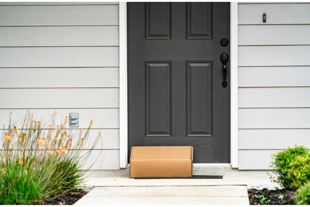 cardboard parcel box on doorstep listing 50 things to stop buying to save money
