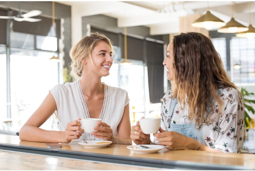 two supportive women having an encouraging conversation over coffee cultivating positive community