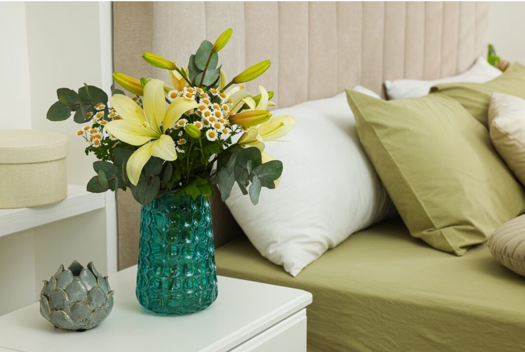 single white flower in slender ceramic vase on wooden nightstand showcasing 30 tiny luxuries every woman deserves