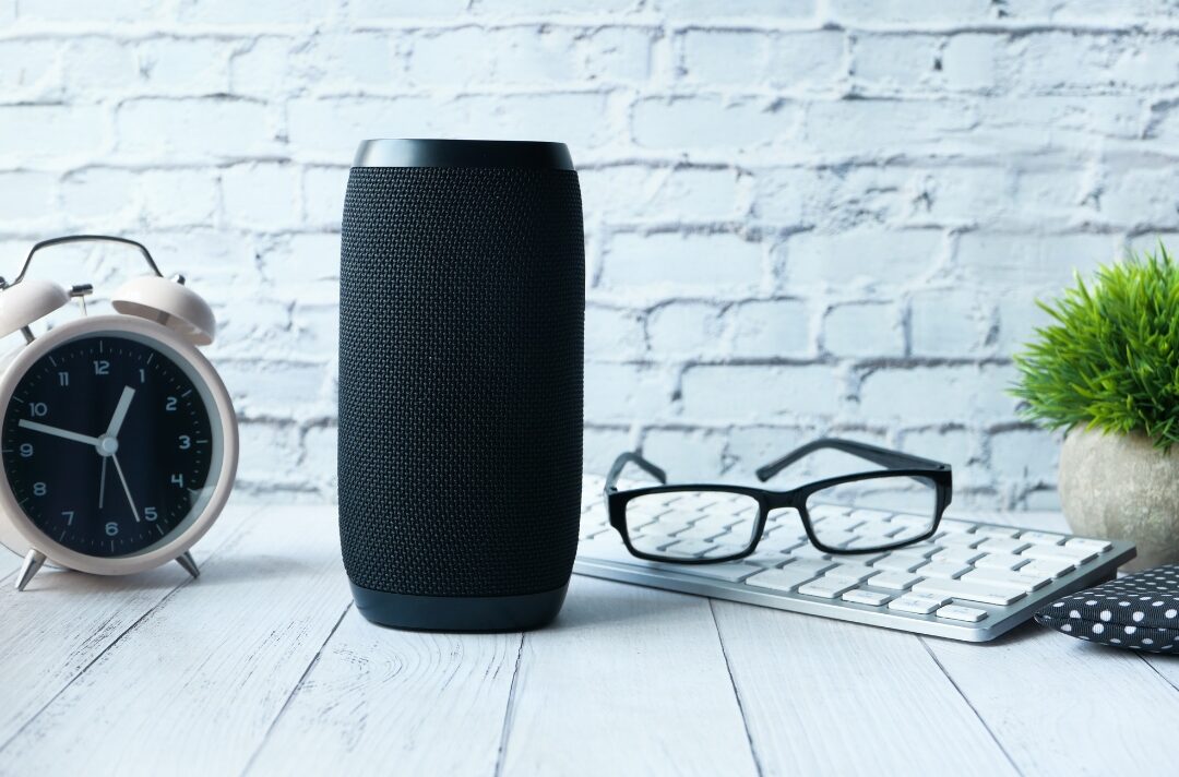 smart speaker on wooden sideboard beside green vase highlighting 30 tiny luxuries every woman deserves