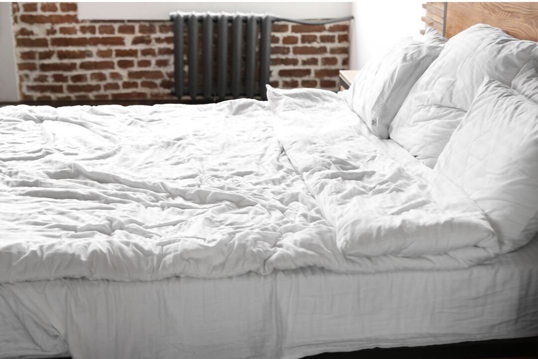 crumpled soft linen bedding in neutral tones on comfortable mattress