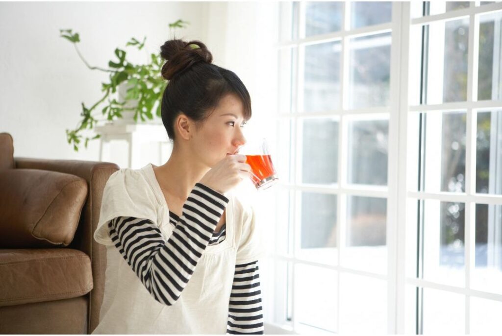 woman sitting alone quietly enjoying cup of tea by window