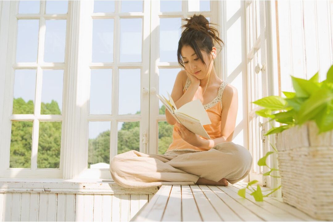 woman sitting in sunlit room reading book uninterrupted presenting 45 daily habits that make life easier