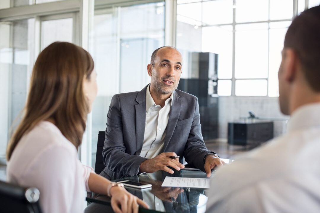 professional fiduciary financial advisor talking with clients in sunlit room