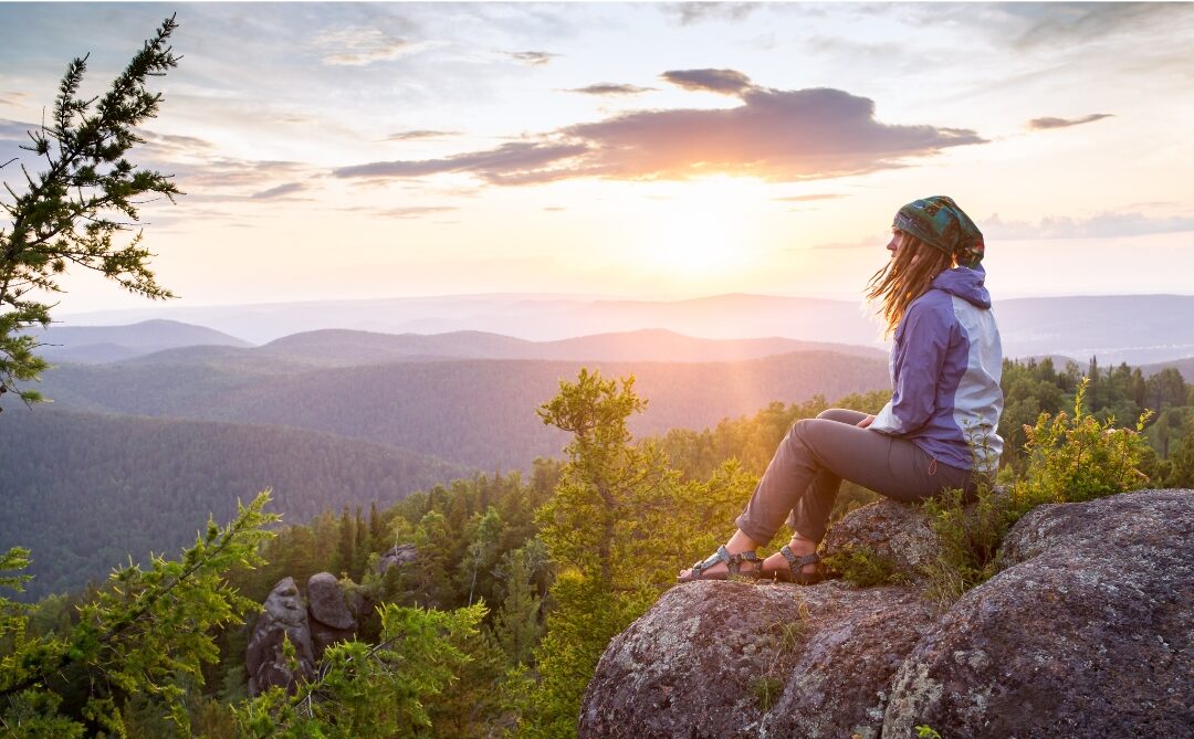 woman standing on sunlit hill looking forward with calm smile mastering things mentally strong moms do differently
