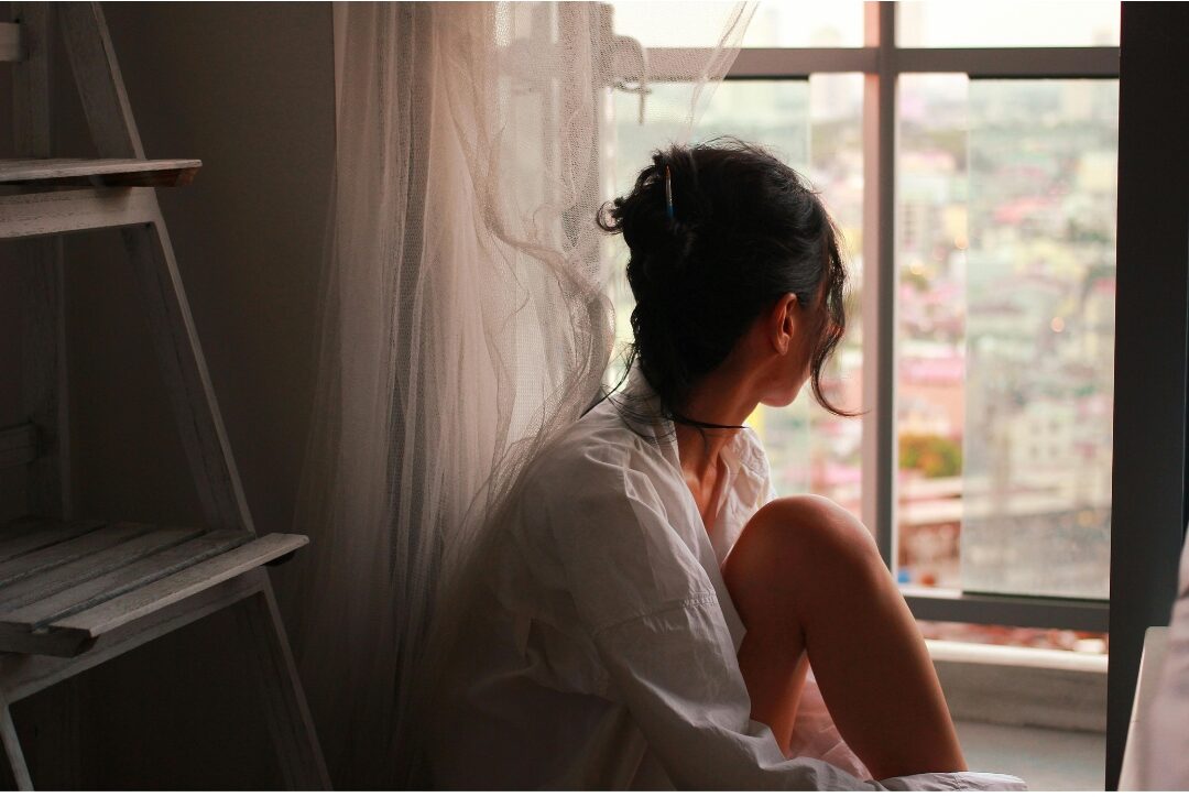 reflective woman sitting peacefully at a clean desk near a window looking forward learning how to stop feeling like you're failing