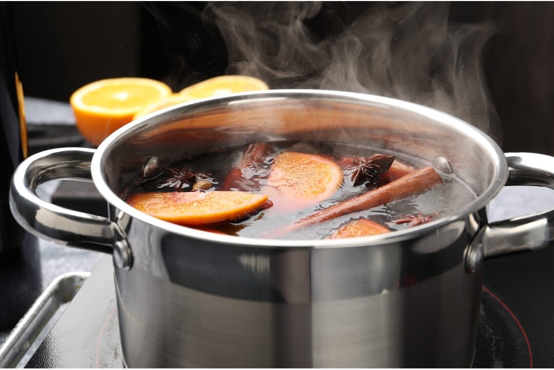 small steel pot simmering cinnamon sticks, orange slices, and cloves on stove highlighting 40 cozy home ideas you'll want to copy