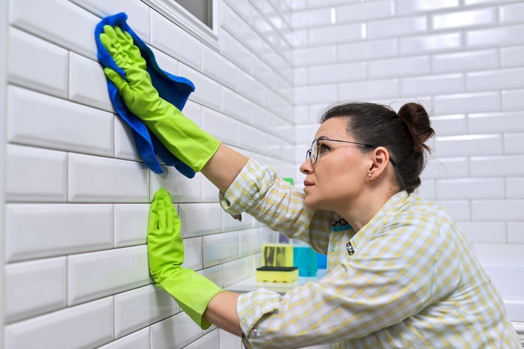 person wiping down bathroom counter with microfiber cloth sequentially showcasing I stopped doing these 12 things my home has never been cleaner
