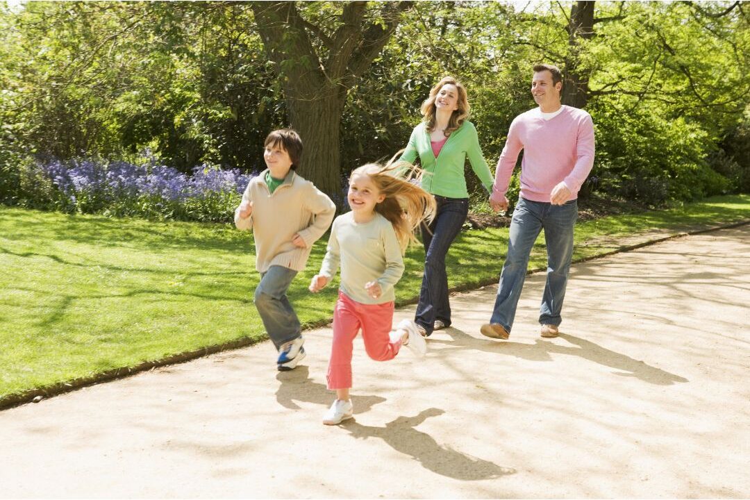 smiling family walking together down sunlit path holding hands highlighting 25 family traditions worth starting