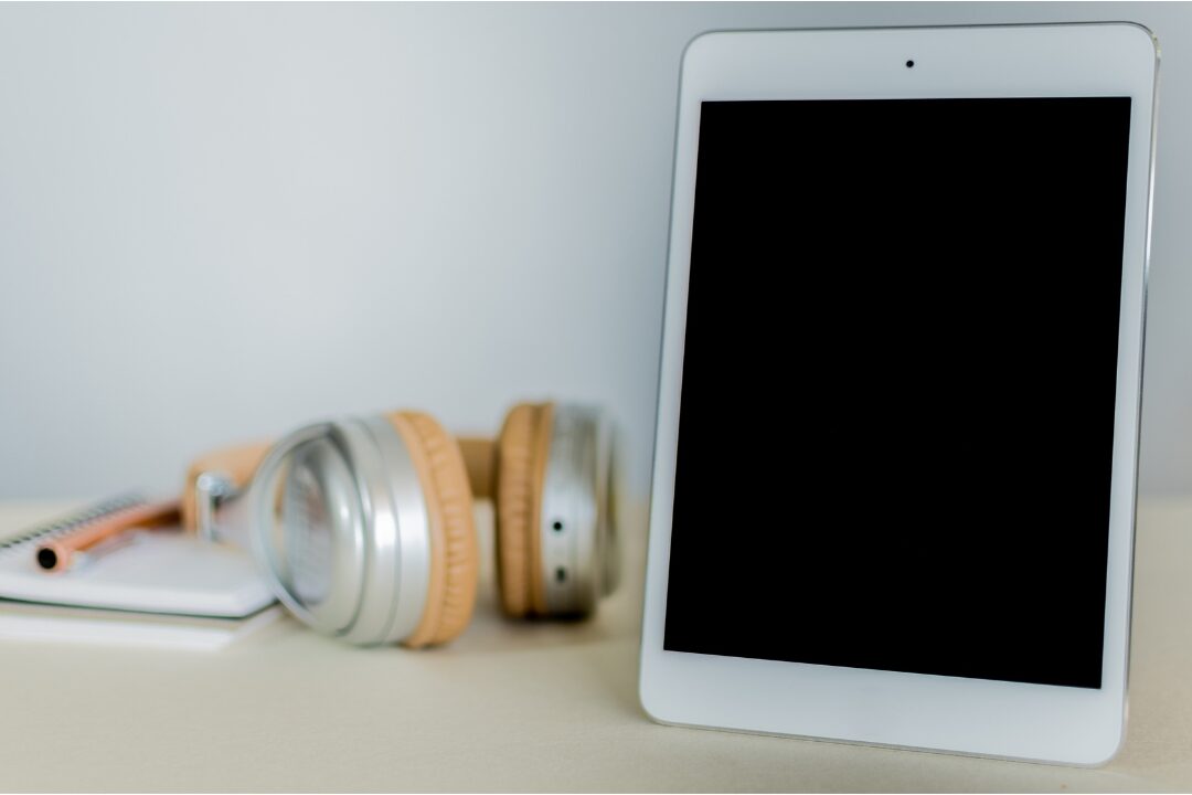 tablet displaying digital reading application resting next to headphones