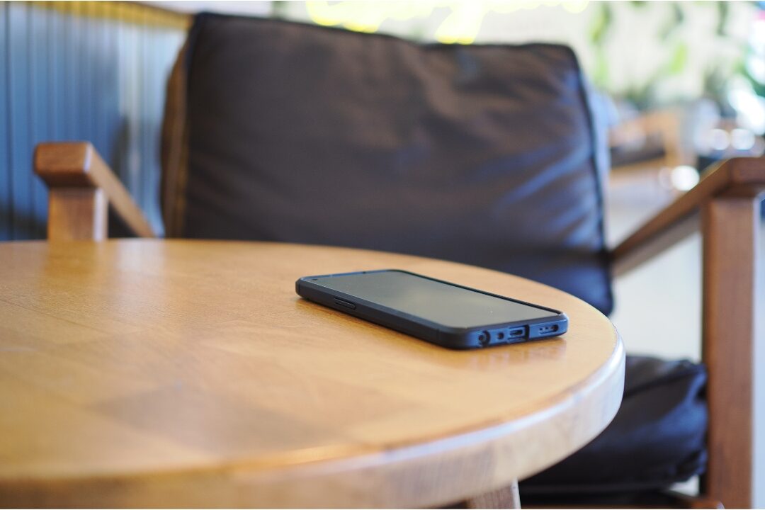 smartphone screen lying face down on clean wooden side table understanding how to separate work life from home life