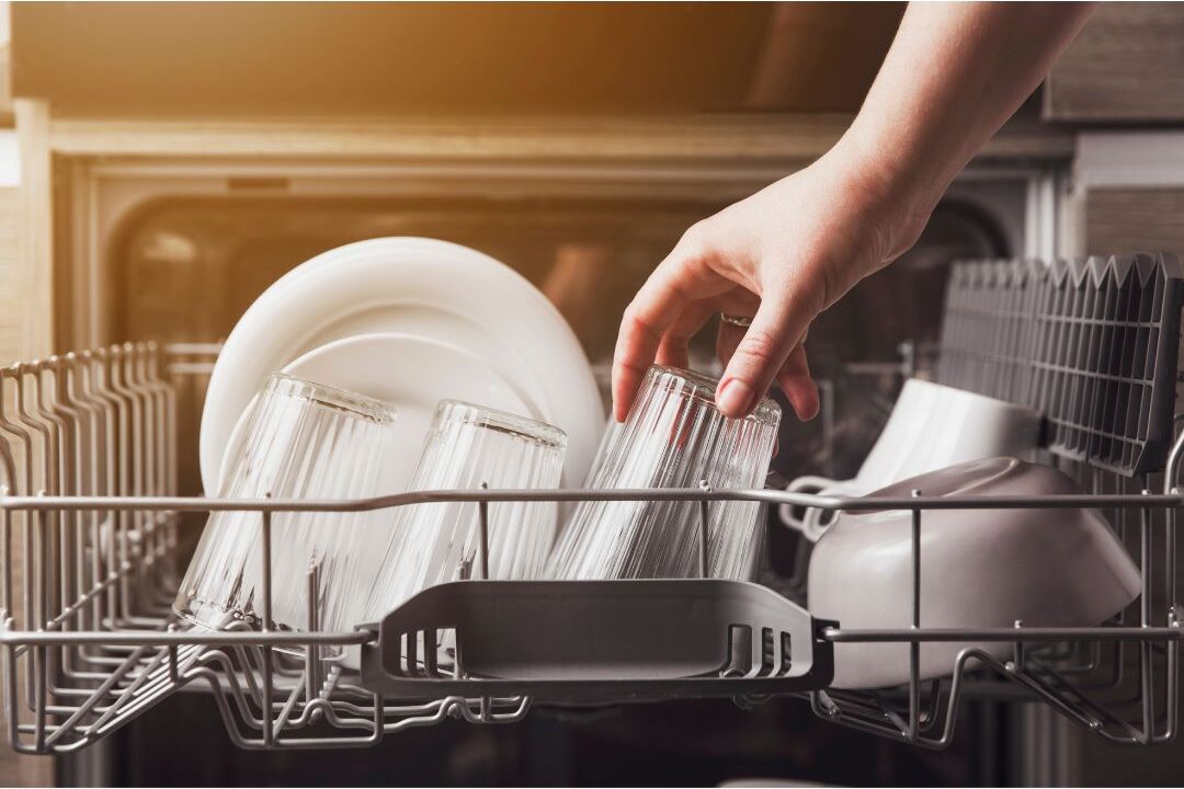 woman placing clean mug directly into open dishwasher