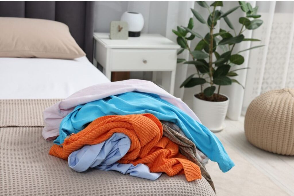 wrinkled laundry piled high on clean bedroom bed
