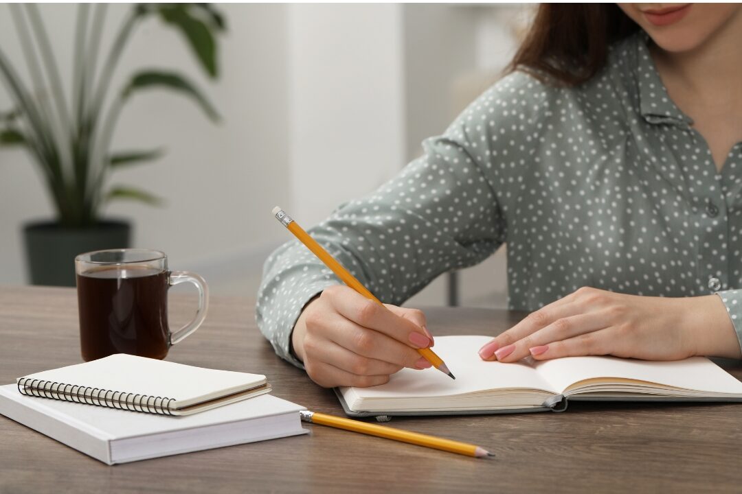 woman writing thoughtfully in planner at warm wooden table adjusting routines