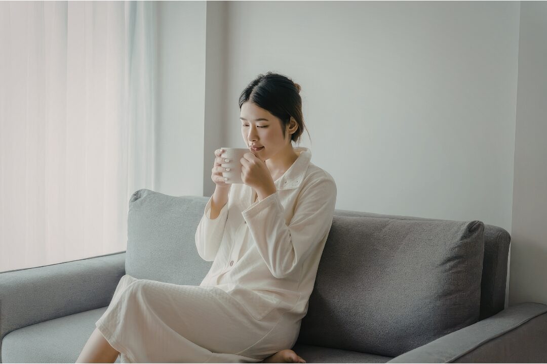 woman sitting peacefully by window holding warm mug in quiet morning light enjoying solitude