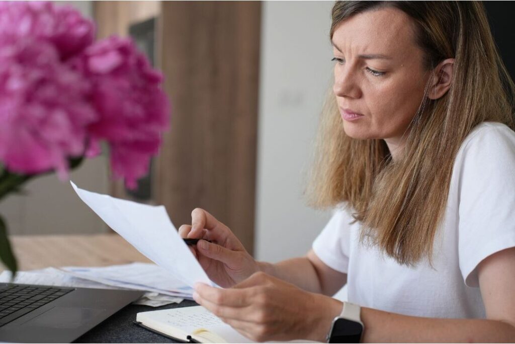 woman reviewing paper notebook for weekly financial check in