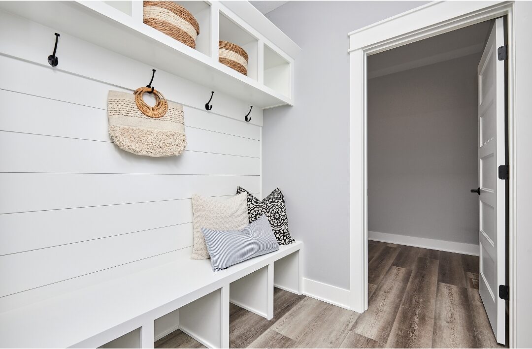 wooden entryway bench with soft cushion, coat hooks, and woven baskets