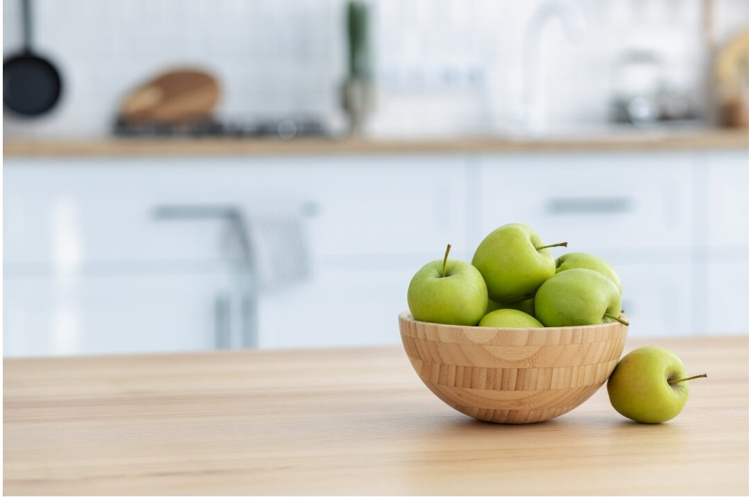 clean wooden kitchen island with a bowl of fresh green apples