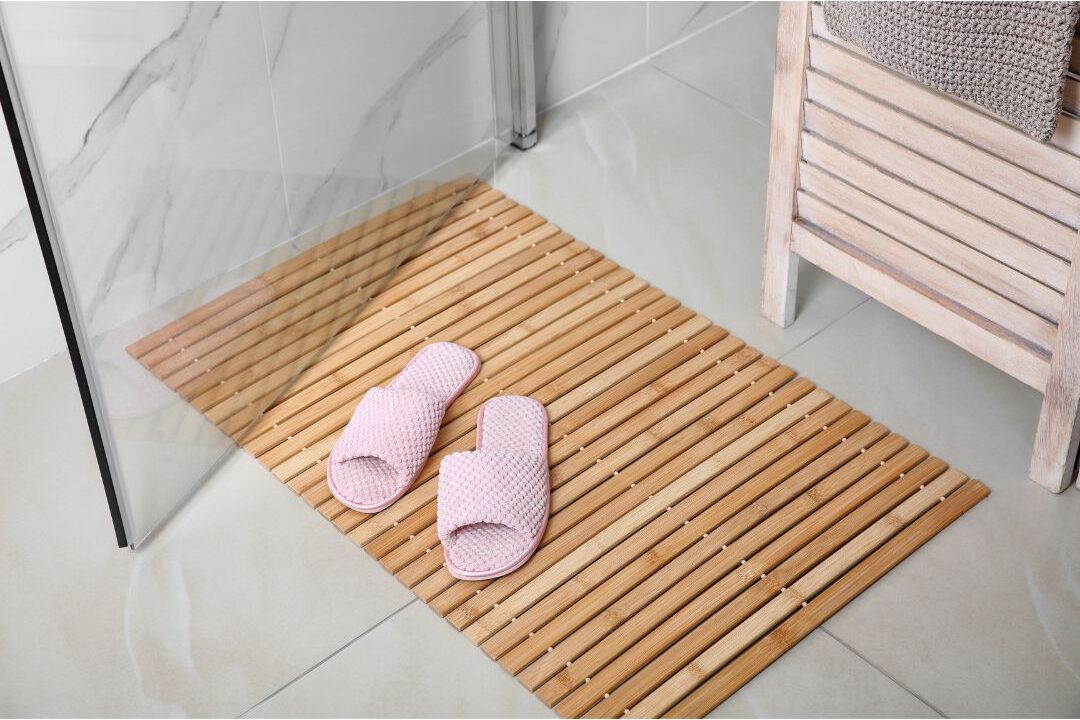 wooden teak bath mat resting outside tiled shower highlighting 70 budget-friendly home upgrades that are actually worth it