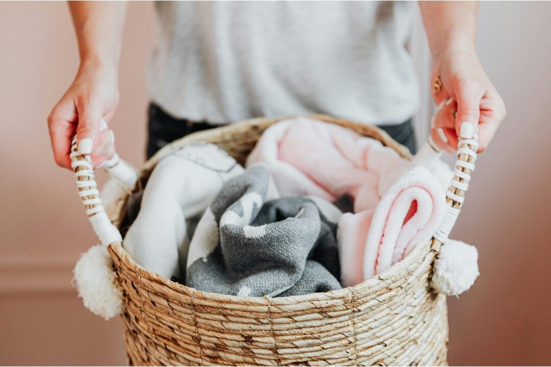 woven seagrass basket overflowing with rolled neutral blankets