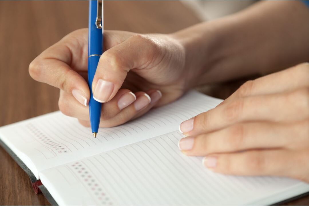 pen writing neatly on small paper pad beside glowing lamp