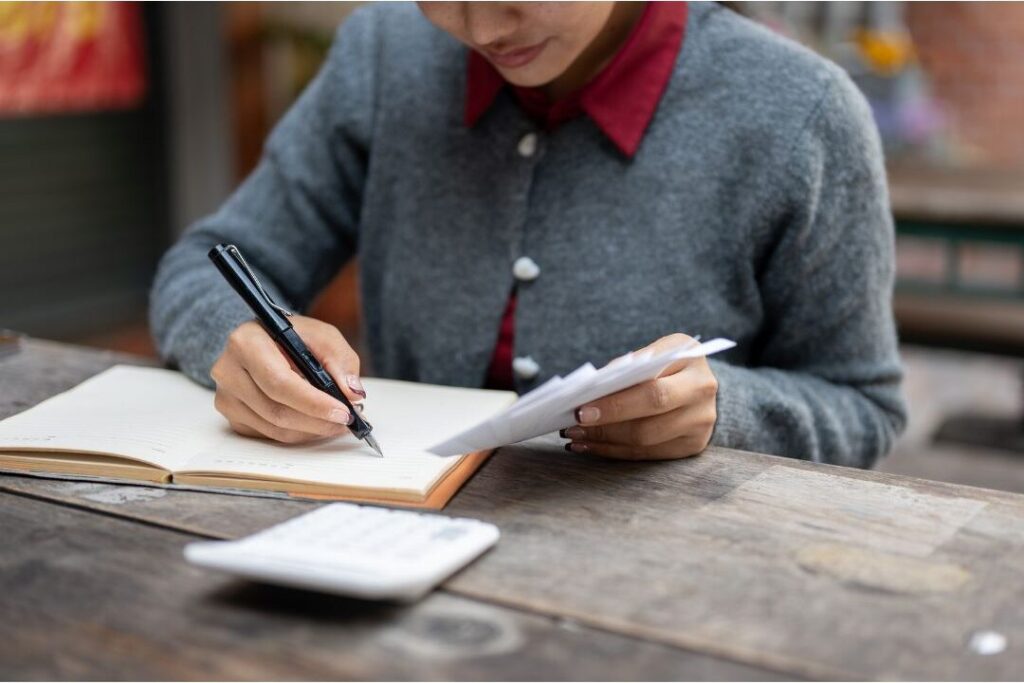 mother writing in notebook conducting zero judgment audit to fix money habits that keep families broke